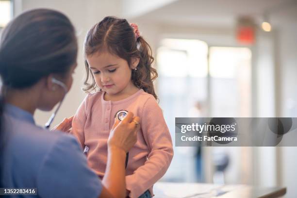 enfermera escuchando el corazón de una niña pequeña - cute nurses fotografías e imágenes de stock