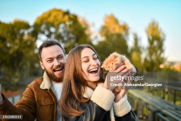 excited couple petting small kitten while taking walk outside - holding cat imagens e fotografias de stock