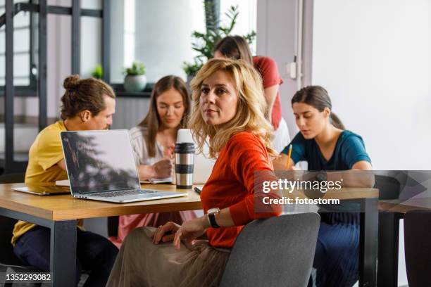 smiling businesswoman looking over shoulder while sitting in a meeting - group people thinking stock pictures, royalty-free photos & images