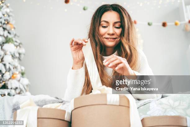 beautiful white woman is opening presents in the morning after new year, smiling with joy - open collar fotografías e imágenes de stock