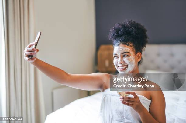 shot of a woman taking a selfie while holding a glass of wine and wearing a face mask - facial cleanse stock pictures, royalty-free photos & images