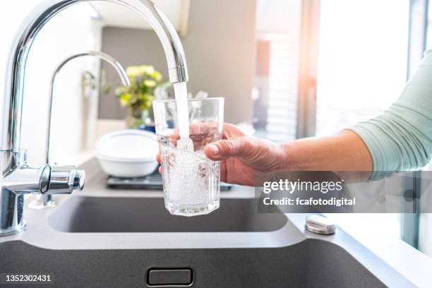 füllglas wasser aus dem wasserhahn - pouring softdrink stock-fotos und bilder