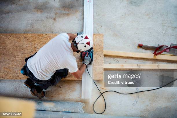 construction worker cutting a plank with an electric saw - snickeriarbete bildbanksfoton och bilder