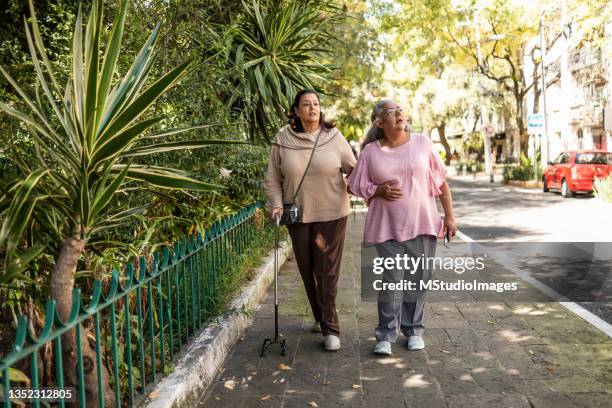 due donne anziane che camminano per il parco - bastone da passeggio foto e immagini stock