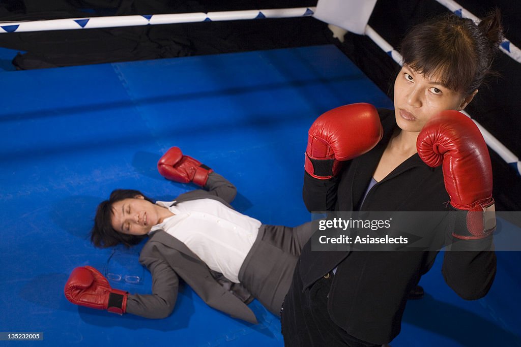 Businesswoman after knocking down her opponent in a boxing ring