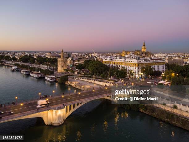 sunset over the seville cityscape with various landmark long the gualdalquivir canal in andalusia, spain - seville stockfoto's en -beelden