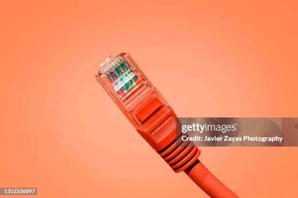 red ethernet cable on red background - cable de ordenador fotografías e imágenes de stock