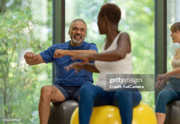 ejercicios de la parte superior del cuerpo en una pelota de yoga - mature coach fotografías e imágenes de stock