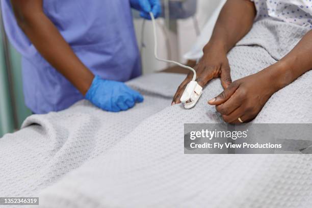 nurse using pulse oximeter on hospitalized patient - pulse oximeter stockfoto's en -beelden