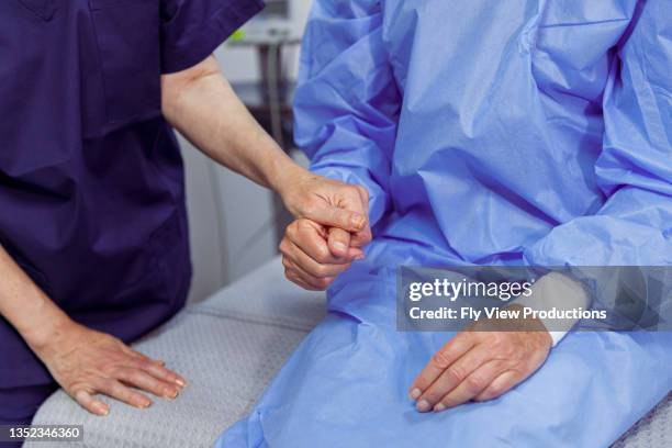 close up of medical professional holding hands with hospitalized patient - postoperatief stockfoto's en -beelden