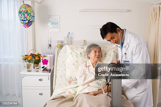 male doctor checking a patient's blood pressure - get well card stockfoto's en -beelden