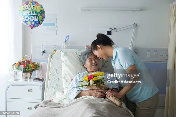 female patient holding a bouquet of flowers with her daughter standing beside her - get well soon stock-fotos und bilder