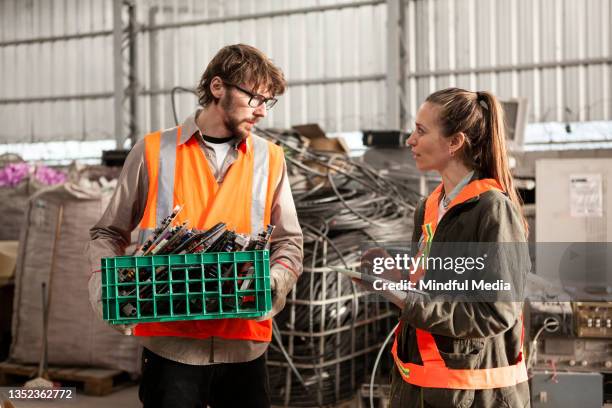 male recycling worker discussing over digital tablet with female coworker - e waste stock pictures, royalty-free photos & images