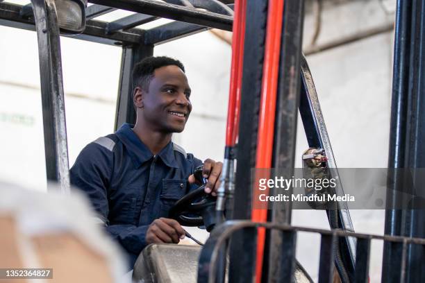 cheerful male worker handling forklift inside recycling centre - material handling stock pictures, royalty-free photos & images