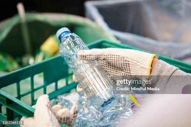 travailleur de la gestion des déchets utilisant des gants de travail tenant une bouteille en plastique - orchestre photos et images de collection