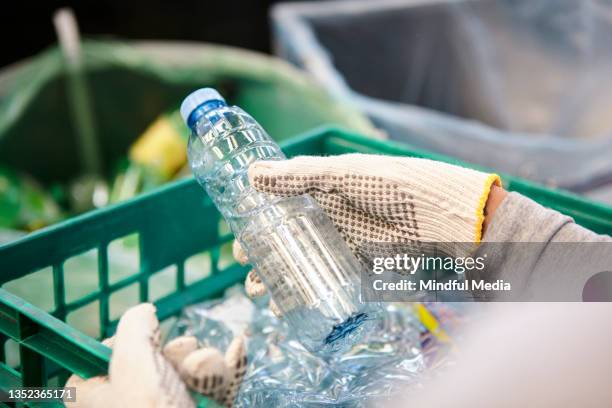 waste management worker using work gloves holding plastic bottle - bottle factory stockfoto's en -beelden