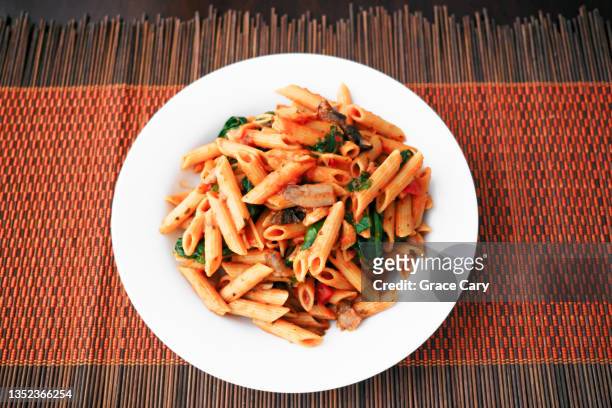 whole wheat penne pasta with mushrooms and spinach - pasta geniessen stock-fotos und bilder