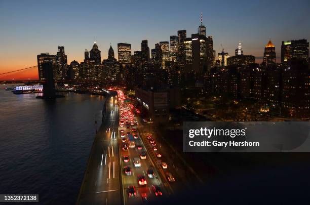 Cars travel on FDR Drive as the sun sets behind lower Manhattan and One World Trade Center on November 9 in New York City.