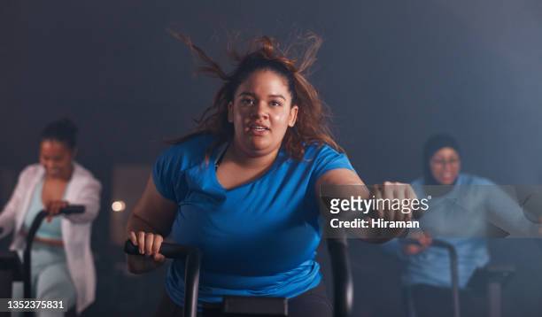 shot of a young woman working out with an exercise bike in a gym - woman twirling stockfoto's en -beelden