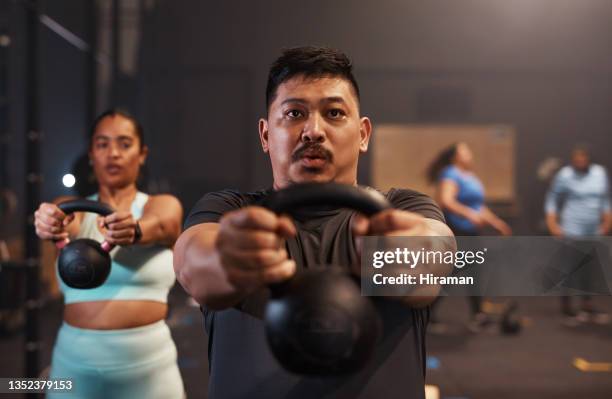 shot of a young man working out with weights in a gym - group gym class bildbanksfoton och bilder