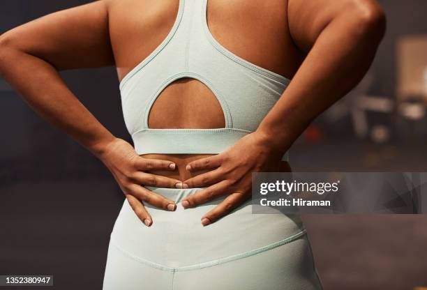 shot of a woman experiencing back pain while working out in a gym - back pain woman stock pictures, royalty-free photos & images