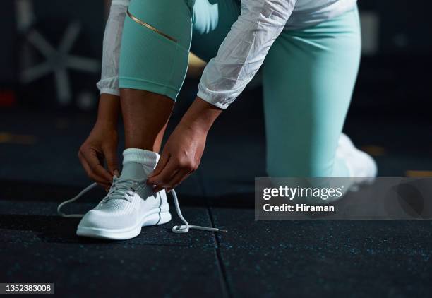 shot of an unrecognizable woman tying her shoelaces before a workout in the gym - fingertier stock pictures, royalty-free photos & images