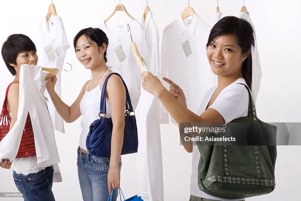 Three young women selecting dresses in a clothing store