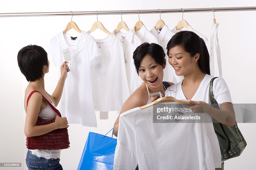 Three young women selecting dresses in a clothing store