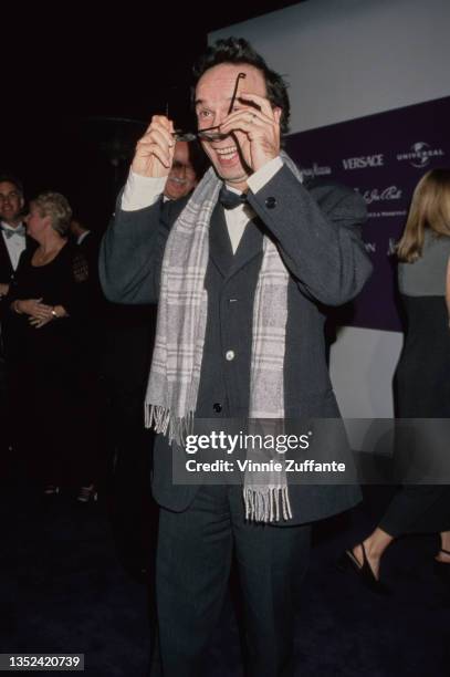 Italian actor and comedian Roberto Benigni, wearing a black tuxedo and bow tie with a grey-and-white plaid scarf, adjusting his glasses at the 9th...