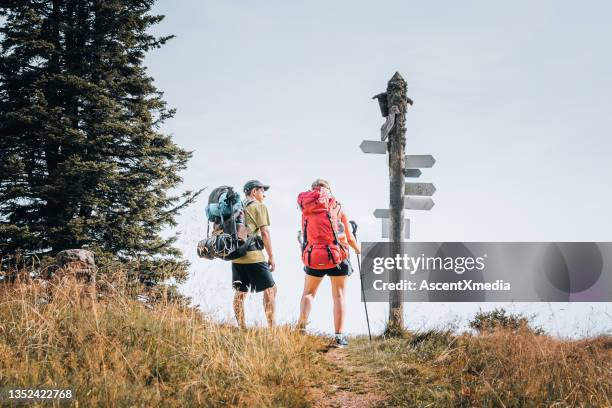 hiking friends relax on grassy mountain ridge - trail marker stock pictures, royalty-free photos & images