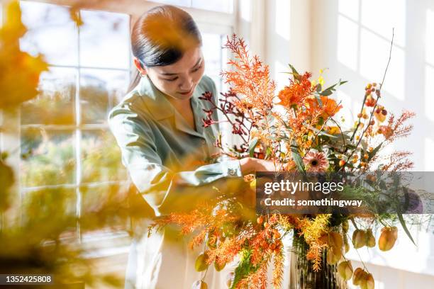 a woman who arranges flowers at home - flower arrangement stock pictures, royalty-free photos & images
