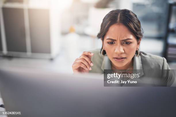 shot of an attractive young businesswoman sitting in the office and looking confused while using her computer - confusion stock pictures, royalty-free photos & images