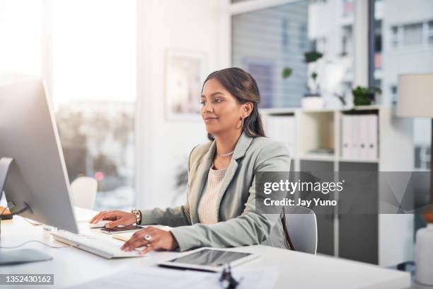 shot of an attractive young businesswoman sitting in the office and using her computer - jay space stock pictures, royalty-free photos & images