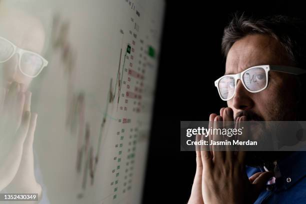 worried businessman looking at graph on smart glass panel - business graph stockfoto's en -beelden