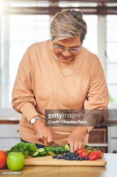 shot of a elderly woman chopping food in a kitchen - paleo diet stock pictures, royalty-free photos & images