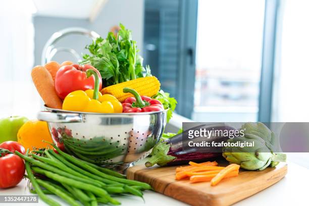 vegan food: fruits and vegetables on kitchen counter - colander imagens e fotografias de stock