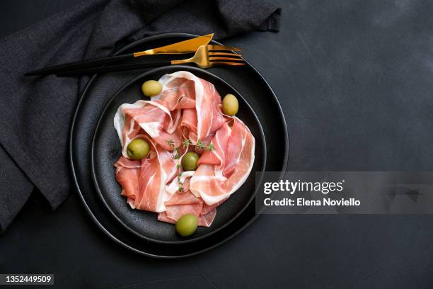 italian pork prosciutto  parma ham with olives on a black dish. traditional antipasto appetizer for dinner or lunch in restaurant. - ham salami bildbanksfoton och bilder
