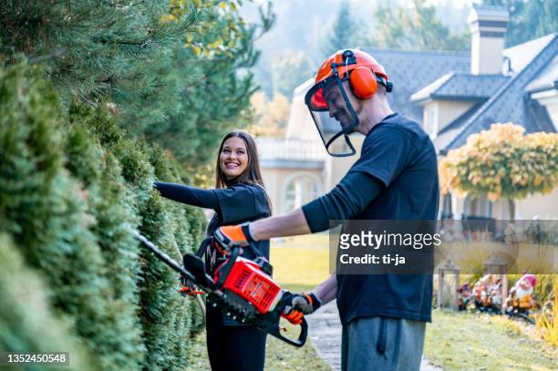 young adult couple trimming a hedge with power saw and - professional landscapers stock pictures, royalty-free photos & images