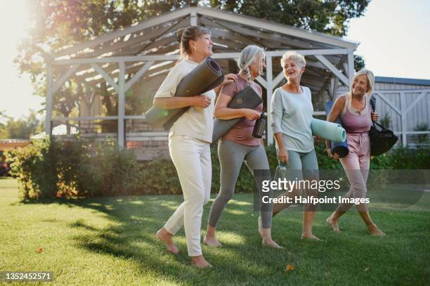cheerful group of senior women talking after exercise outdoors in park. - senioren spazieren sommer stock-fotos und bilder