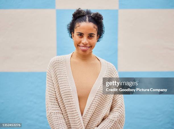 jeune femme souriante portant un pull devant un mur coloré à l’extérieur - cardigan sweater photos et images de collection
