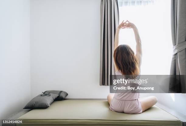 back view of young woman raised her arms for stretching in bed after wake up in the morning. - seize the day bed private view stock pictures, royalty-free photos & images