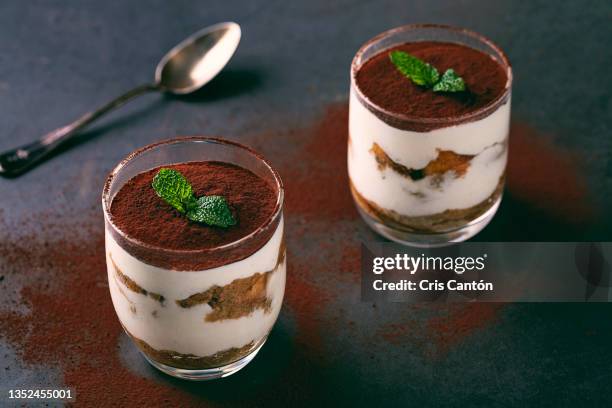 two glasses of tiramisu on black background - mascarpone stock pictures, royalty-free photos & images