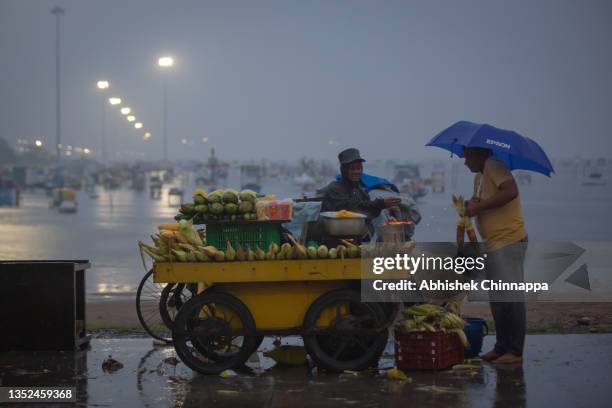 Man buys corn on the cob from a street vendor on a rainy day on Marina beach on November 10, 2021 in Chennai, India. As the world was discussing the...