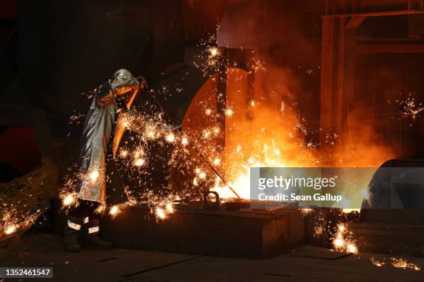 Sparks fly as a worker takes a sample of molten iron flowing from a blast furnace at the Thyssenkrupp Steel Europe steelworks on November 09, 2021 in...