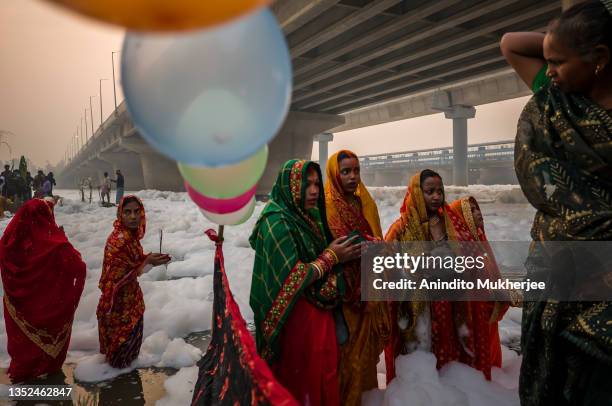 Hindu devotees take a dip in the waters of River Yamuna amid toxic foam caused by pollution on the occasion of Chhat puja on November 10, 2021 in...