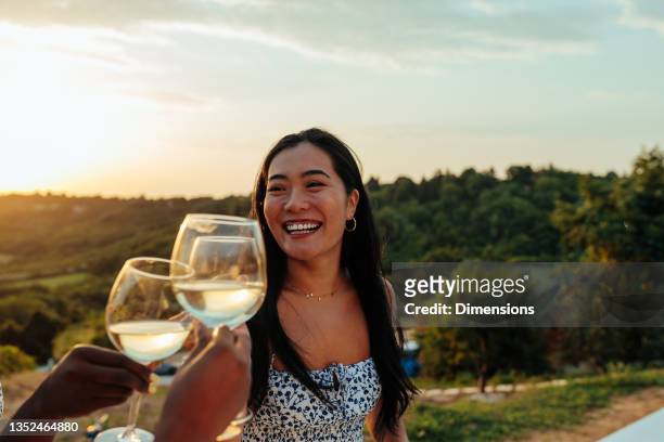 asian woman toasting with friends at outdoors party - vinyard stock pictures, royalty-free photos & images