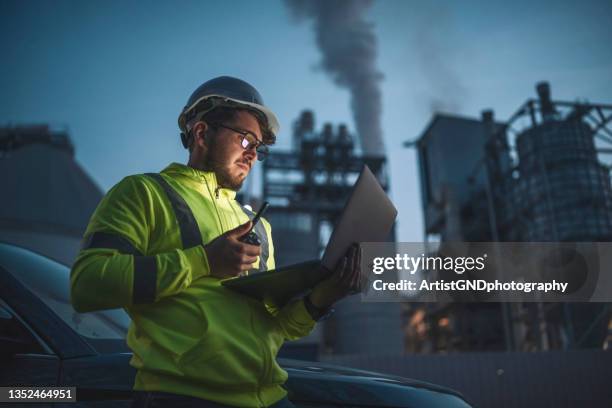 konzentrierter ingenieur, der während der nachtschicht in der gas- und ölindustriestation mit laptop arbeitet. - atomic imagery stock-fotos und bilder