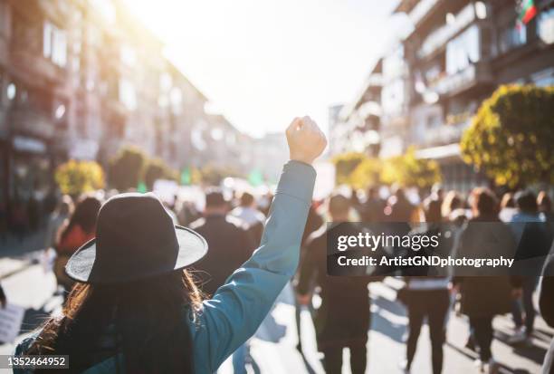 junge demonstrantin, die ihre faust hebt - protests take place around europe stock-fotos und bilder