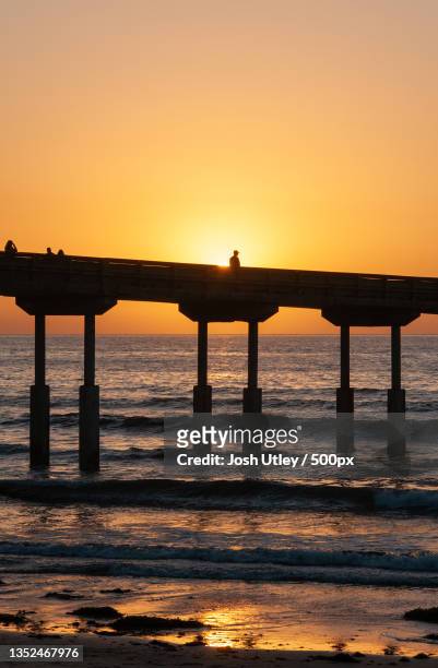 silhouette of pier on sea against clear sky during sunset,ocean beach,united states,usa - josh utley stock-fotos und bilder