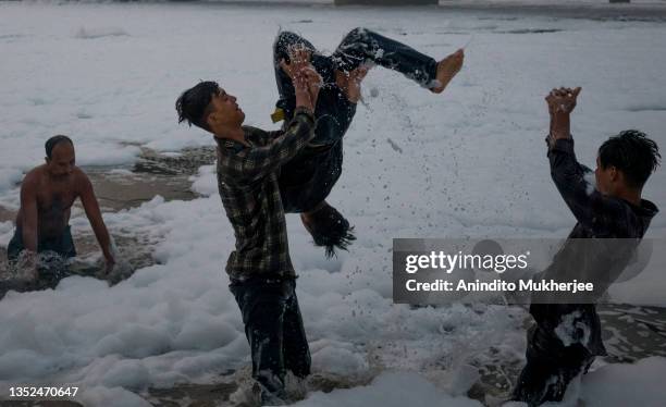 Boys play as they take a dip in the waters of River Yamuna amid toxic foam caused by pollution on the occasion of Chhat puja on November 10, 2021 in...